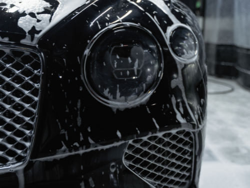 Schwarzer Bentley mit Seifenblasen während der Autowäsche.
