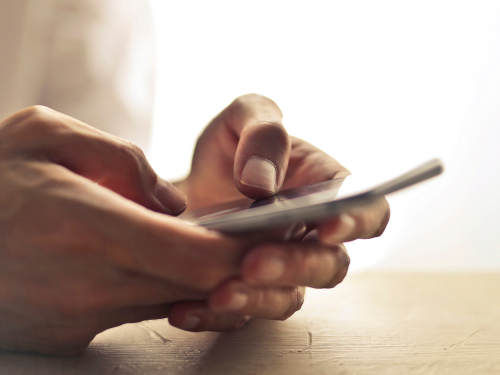 Hände halten ein Smartphone, während sie darauf tippen.