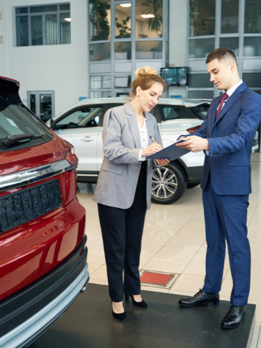 Frau und Mann beraten sich in einem Autohaus über ein Fahrzeug.