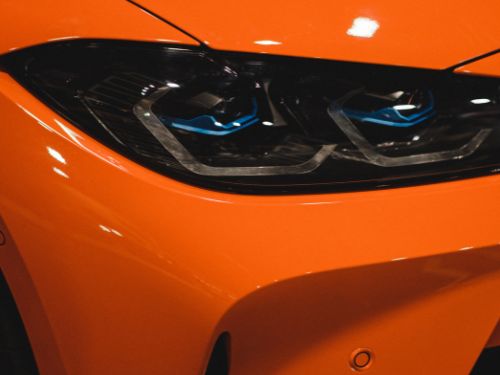 Scheinwerfer eines orangefarbenen Autos mit blauen Akzenten.