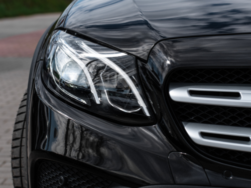Schwarzes Auto mit betontem Scheinwerferdesign auf grauem Asphalt.