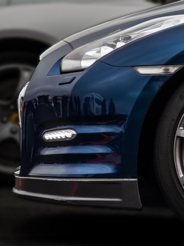 Blauer Sportwagen mit markanten Scheinwerfern und Spoiler-Design.